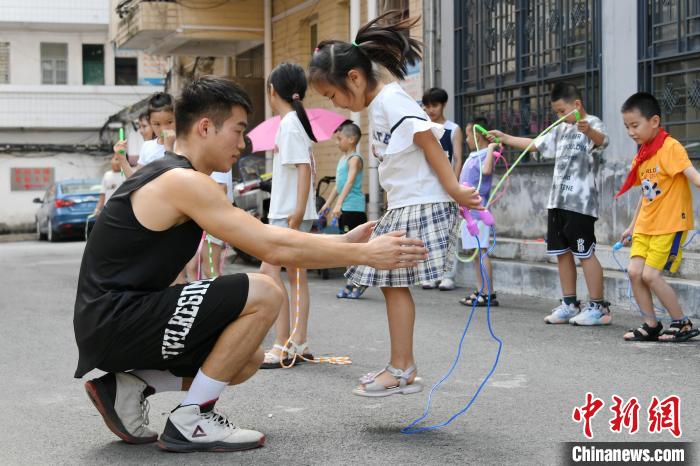 图为大学生志愿者在教孩子们学跳绳。　廖光福 摄