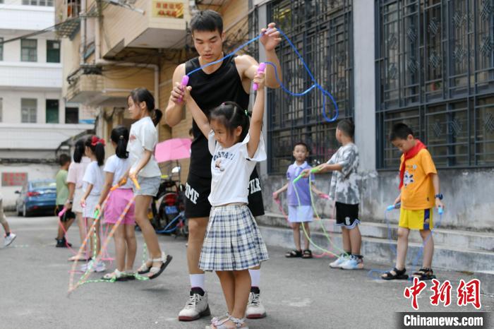 图为大学生志愿者在教孩子们学跳绳。　廖光福 摄